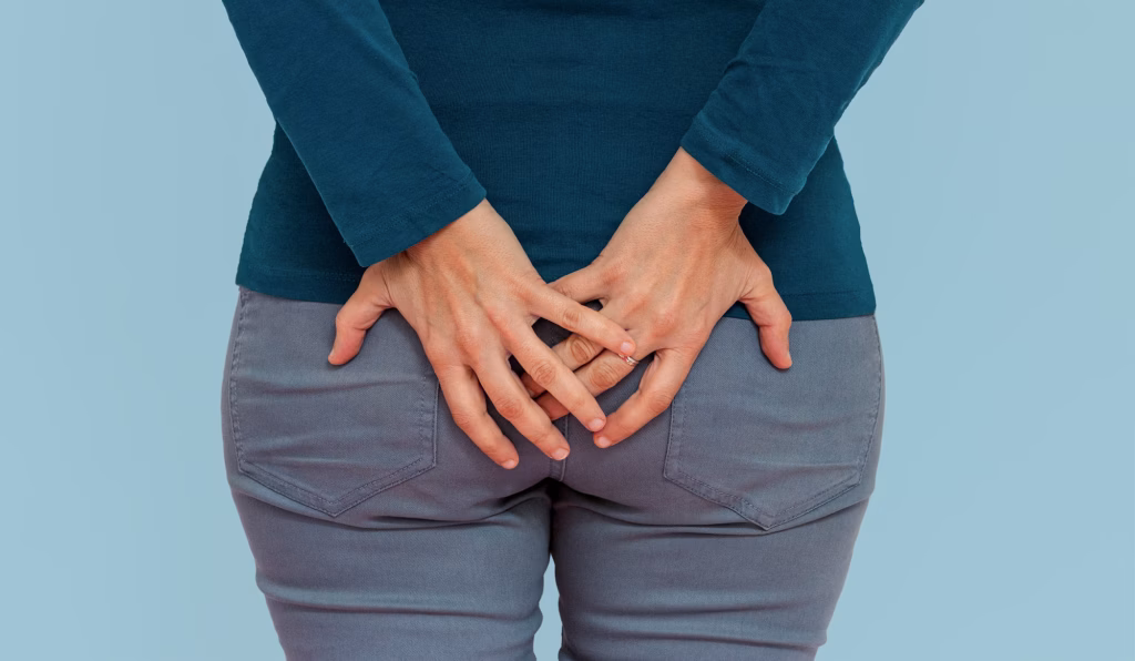 Neurogene Blasen- / Darmfunktionsstörung/ Inkontinenz: Damenkorso in grauer Jeans und blauem Pullover hält Hände auf ihrem Gesäß.